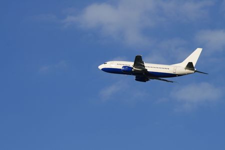 Modern passenger plane flying in blue sky with clouds