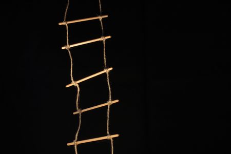 Alight rope-ladder hanging on deep dark backgroundの写真素材