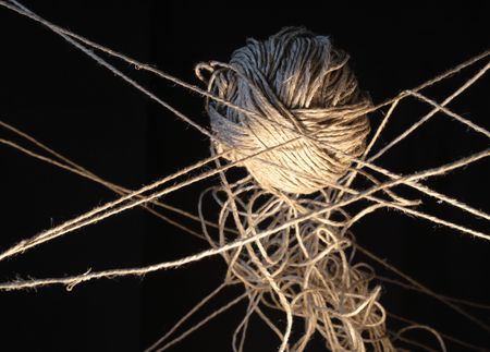 Clew and tangled ropes hanging on dark background