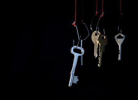 Manifold keys hanging on red rope with fish-hooks on dark backgroundの写真素材
