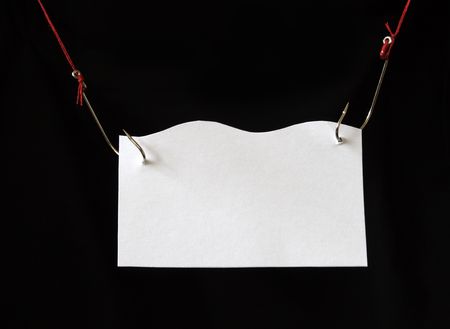 White papery nameboard hanging with fish-hooks on dark backgroundの写真素材
