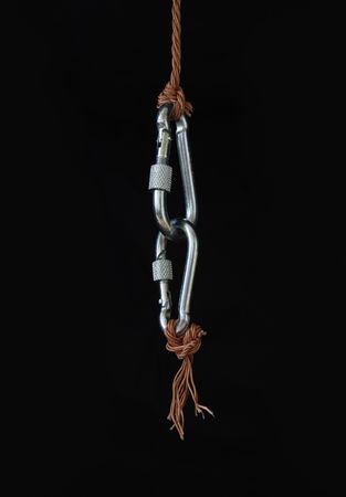 Two fastened clasps hanging with rope on black backgroundの写真素材