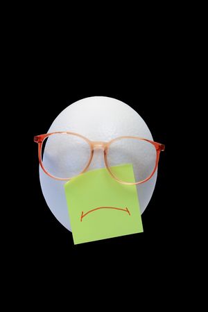 Sad face made from ostrich egg and spectacles on black background