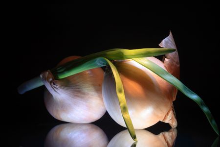 Close-up of onion with reverberation lying on dark glassy backgroundの写真素材