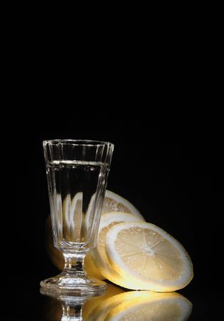 Nice little glass of vodka on dark background with yellow lemonの写真素材