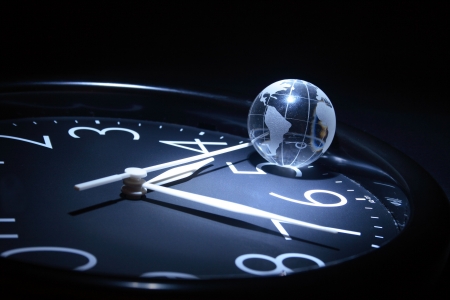 Litte glassy globe on dark background with watch