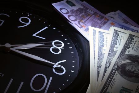Round clock with mooving second hand and money as dark backgroundの写真素材
