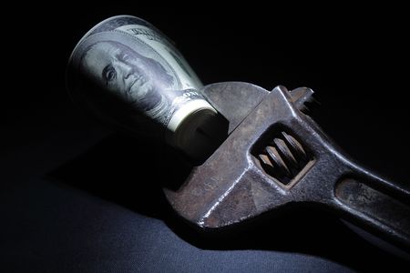 Rusty  spanner with dollar's bundle on dark backgroundの写真素材