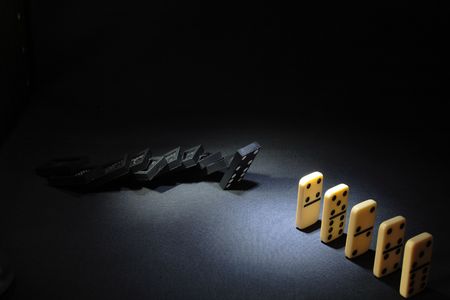 Black and white dominoes standing on dark backgroundの写真素材