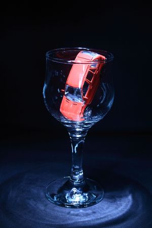 Little red toy car inside empty wineglass on dark backgroundの写真素材