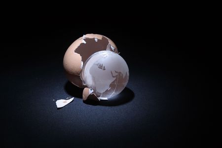 Eggshell with glassy globe lying on dark backgroundの写真素材