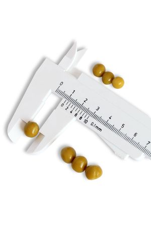 Vernier calliper with some peas isolated on white backgroundの写真素材