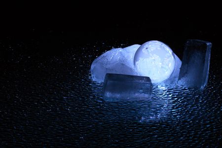 Dark background with glassy globe inside block of iceの写真素材