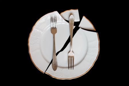 Two forks lying on broken plate isolated on black backgroundの写真素材