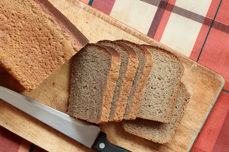 Slices of rye-bread with kitchen knife lying on breadboard