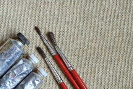 Tubes of oil paint and brushes on canvas backgroundの写真素材