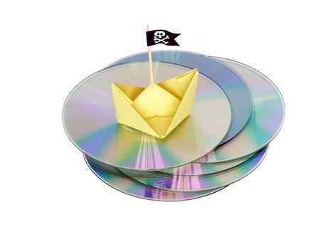 Paper boat with black piratic flag standing on compact disk's pile isolated on whiteの写真素材