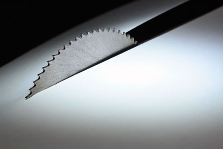 Circular saw cutting white paper sheet on dark backgroundの写真素材