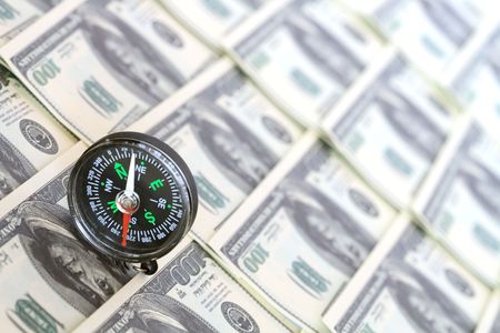 Compass standing on background with one hundred dollar banknotesの写真素材