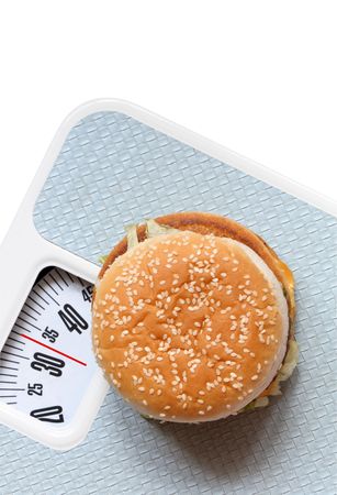 Hamburger lying on bathroom scale isolated on white with pathの写真素材