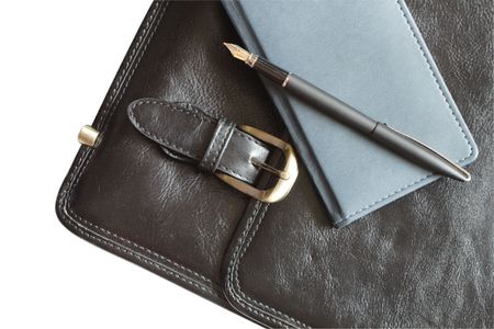 Pen and notebook lying on black leather brief case.の写真素材