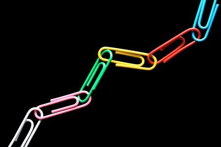 Chain made from multi-colored paper clips on a black background. 