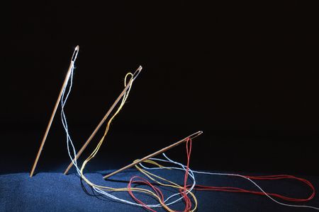 Closeup of three sewing needles standing on black backgroundの写真素材