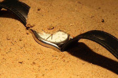 Closeup of hand watch lying on sand backgroundの写真素材