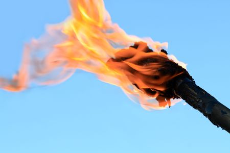 Closeup of flaming torch on blue background with copy spaceの写真素材