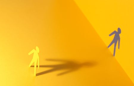 Paper man standing against his outline cutting in paper wallの写真素材