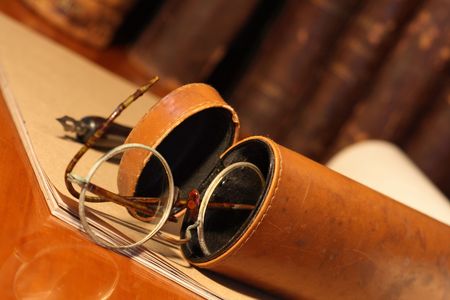 Closeup of old spectacles inside leather case on background with bookの写真素材