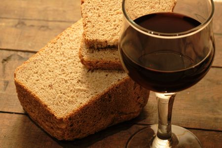Closeup of rye bread and goblet of red wine on wooden backgroundの写真素材