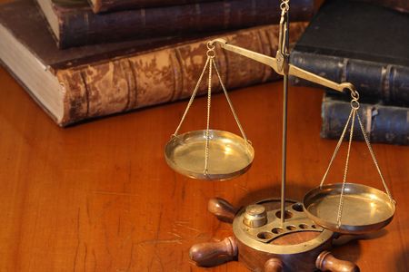 Ancient weight scale standing on wooden table near old booksの写真素材