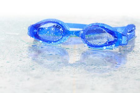 Blue wet swimming goggles on glass background with water dropsの写真素材