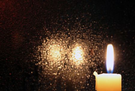 Candle with burning flame on dark glass background with reverberationの写真素材
