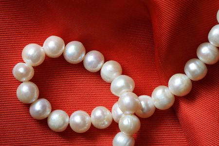 Closeup of pearl necklace lying on red textile backgroundの写真素材