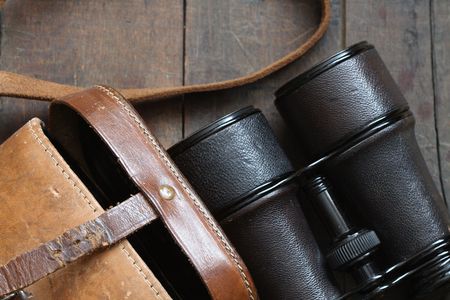 Closeup of old binoculars and leather case on wooden backgroundの写真素材