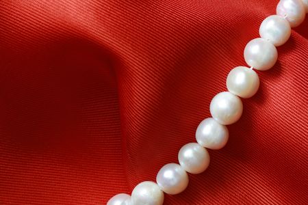 Closeup of pearl necklace lying on red textile backgroundの写真素材