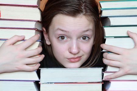 Portrait of nice young girl inside stacks of booksの写真素材