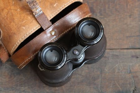 Closeup of old binoculars and leather case on wooden backgroundの写真素材
