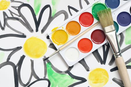 Watercolor paints palette and paintbrush lying on paper sheet with painted flowersの写真素材