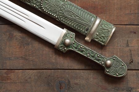 Closeup of antique caucasian dagger and scabbard on wooden backgroundの写真素材