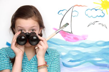 Nice young girl holding old binoculars on background with painted sea landscapeの写真素材
