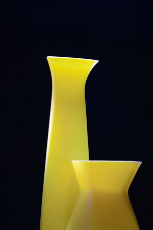 Closeup of nice modern yellow vases isolated on black backgroundの写真素材