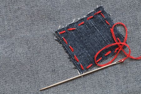 Needle and patch with red thread attached on jeans texturedの写真素材