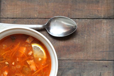 A plate with spicy soup of vegetables and meat on wooden tableの写真素材