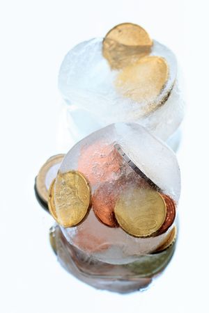 Coins inside ice cubes isolated on blue backgroundの写真素材