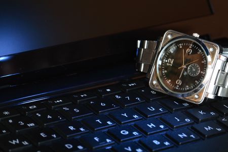 Closeup of steel wristwatch lying on black computer keyboardの写真素材