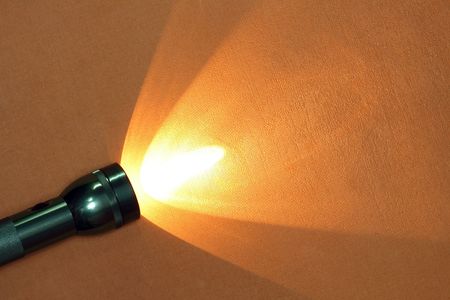 Modern aluminium luminous flashlight on ginger background with copy spaceの写真素材