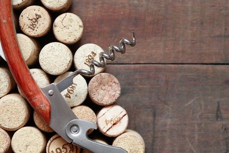 Closeup of corkscrew lying on wine corks on wooden backgroundの写真素材